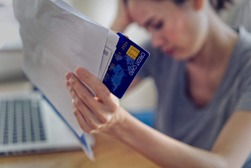 Stressed young sitting Asian woman hands holding credit card