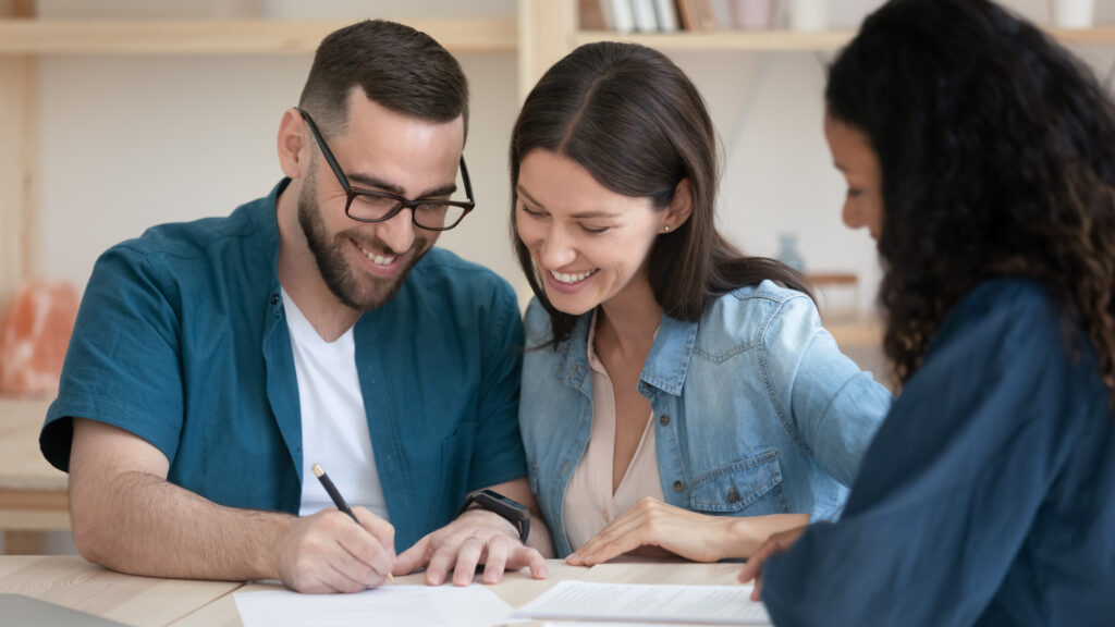 Happy family couple signing contract with agent