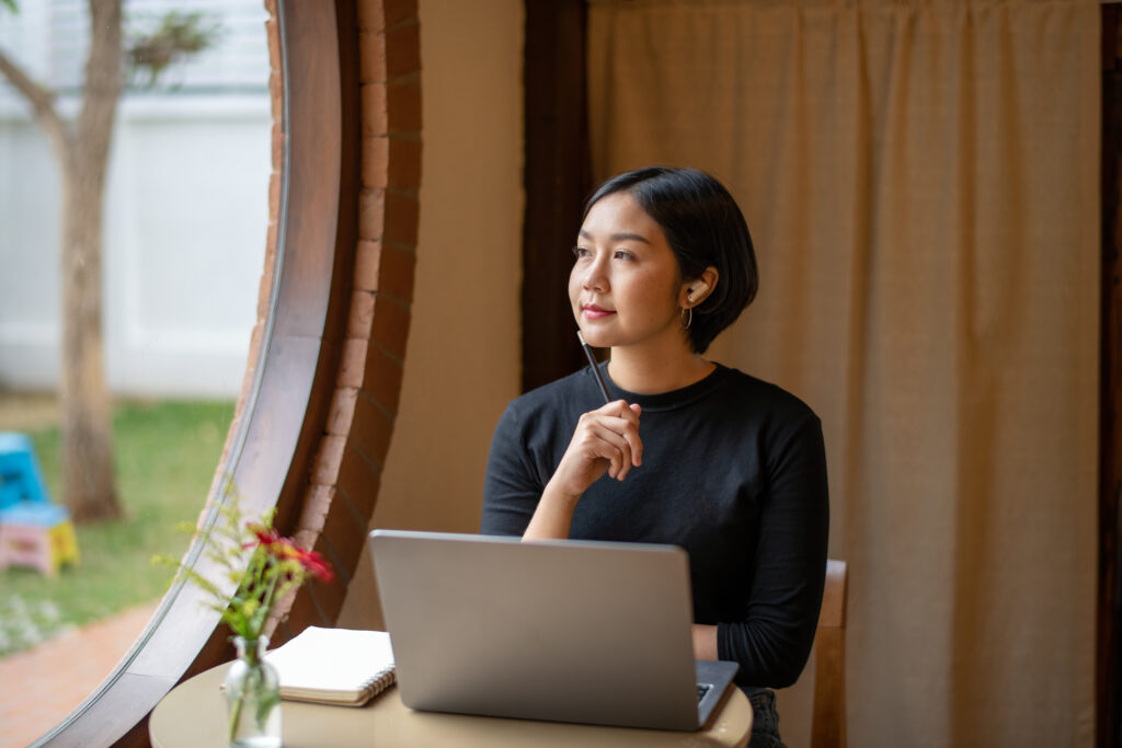 Freelance businesswoman sitting in front of her considering work at cafe, thinking new project work plan.