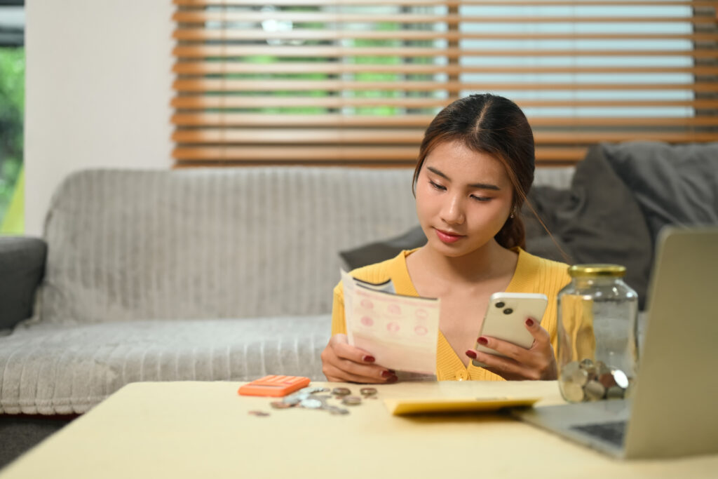 Young woman paying domestic bills or managing online banking on her mobile phone